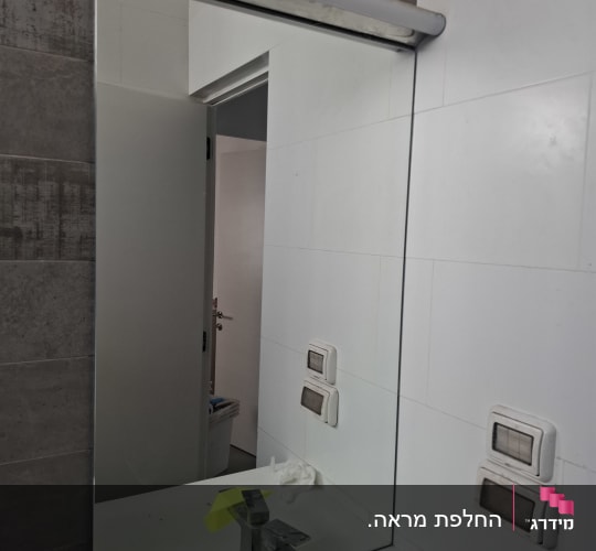 מראה בחדר אמבטיה עם כיור וברז